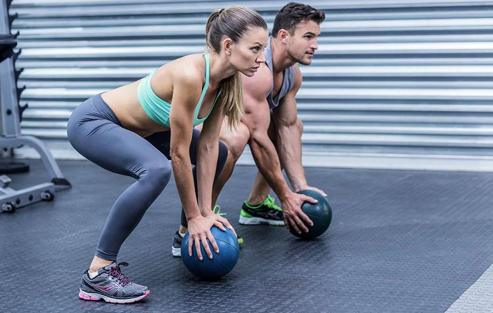 Two people working out with medicine balls